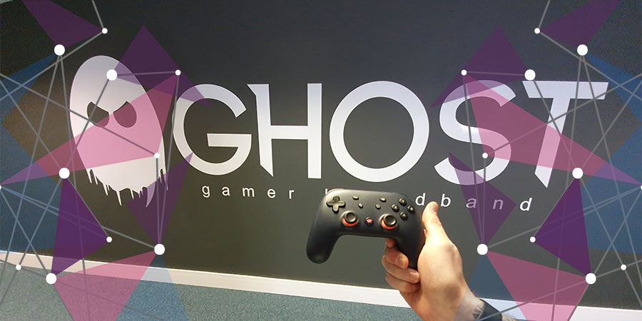 Black Stadia controller in front of Ghost Gamer Broadband wall